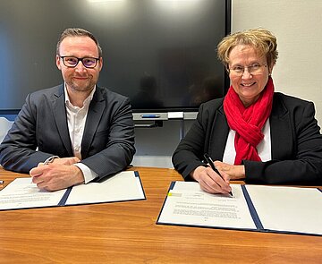 Pascal Rastetter und Erste Bürgermeisterin Gabriele Luczak-Schwarz unterschreiben die Vertragsverlängerung.
