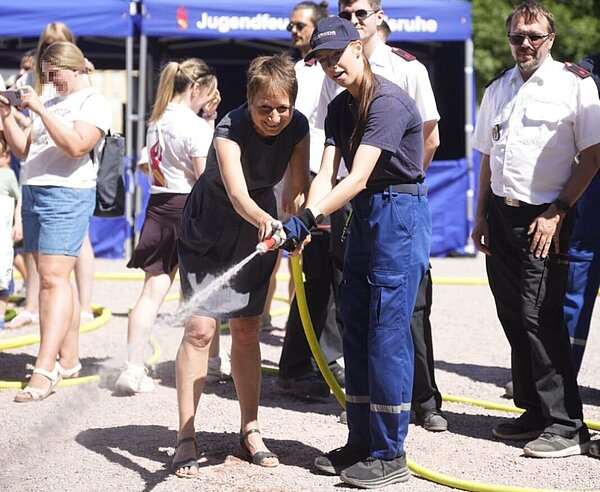 Erste Bürgermeisterin Bettina Lisbach informiert sich beim Rundgang über das Jubiläumsfest der Berufsfeuerwehr Karlsruhe unter anderem an der Station der Jugendfeuerwehr über die vielfältigen Aufgaben der Blaulichtorganisationen und darf auch selbst Hand anlegen.