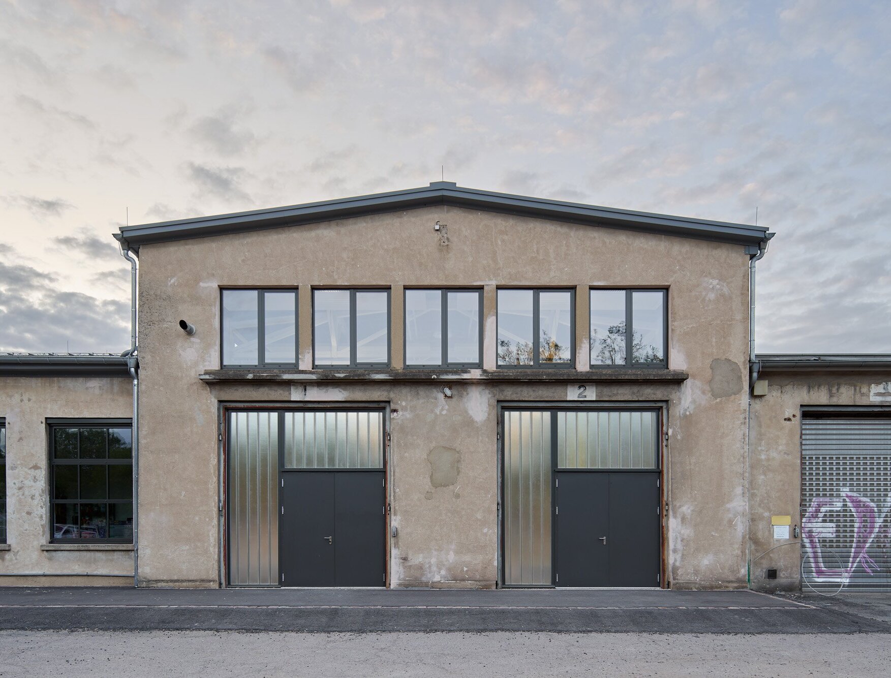 Das Bild zeigt die Südostfassade der ehemaligen Reparaturhalle im unveränderten äußeren Erscheinungsbild, die im Inneren zu einem Trainingsbereich für Zirkus- und Jugendgruppen umgebaut wurde.