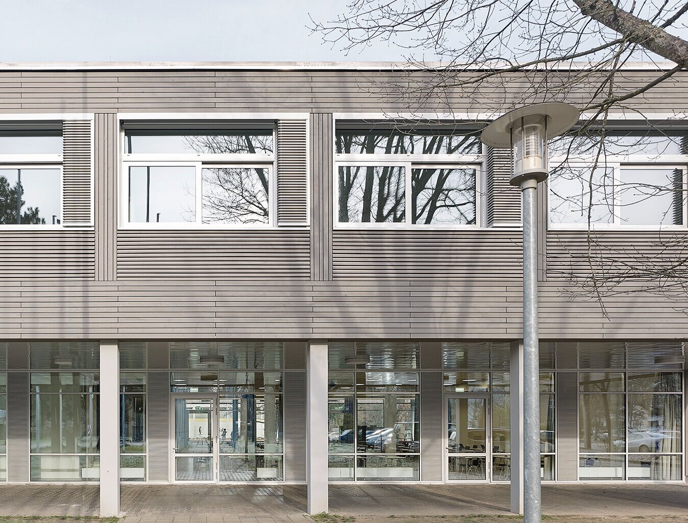 Zu sehen ist eine Detailaufnahme der grau lasierten Holzfassade und der neuen Fensterelementen.