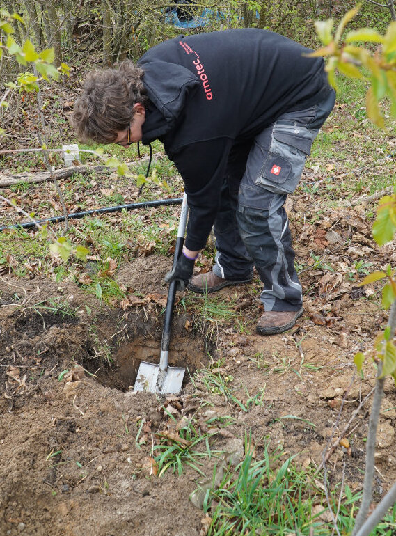 Person gebeugt, gräbt ein Loch mit dem Spaten