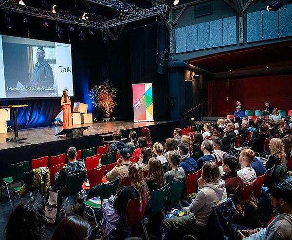 Rednerin auf einer Bühne vor Publikum