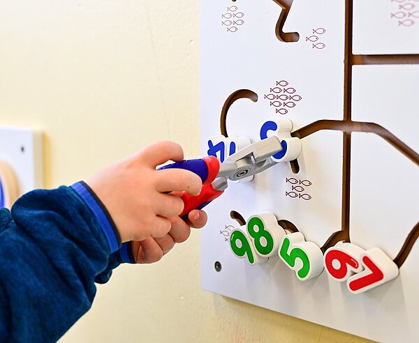 Kind spielt Schiebe-Spiel an der Wand