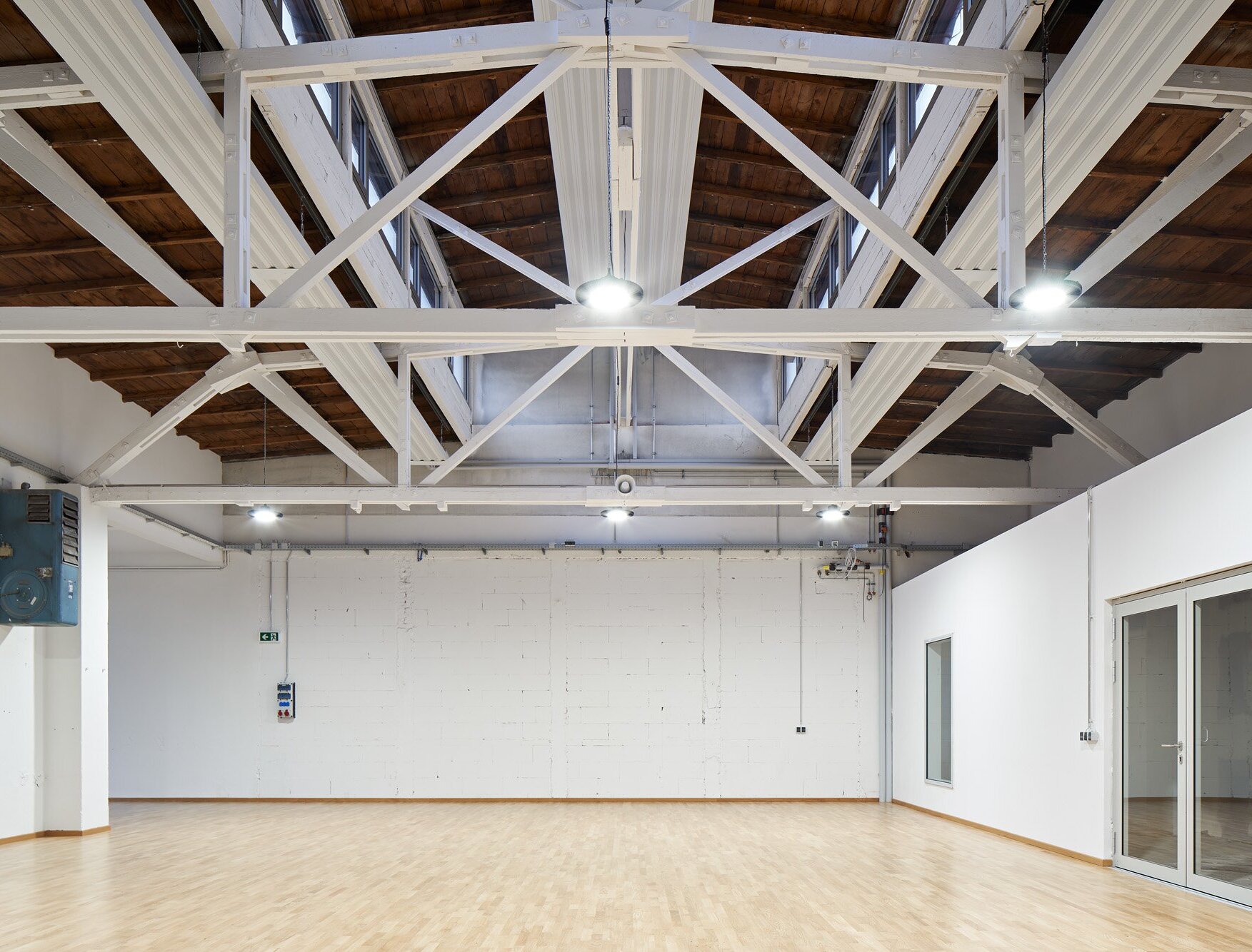 Zu sehen ist einer der Bewegungsräume mit hölzernem Schwingboden und dem beeindruckenden, sichtbaren Dachtragwerk.