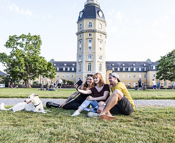Das Bild zeigt Studierende mit einem Hund im Schlossgarten.