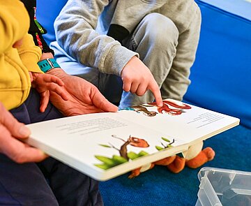 Kinder und Erzieher lesen gemeinsam ein Buch