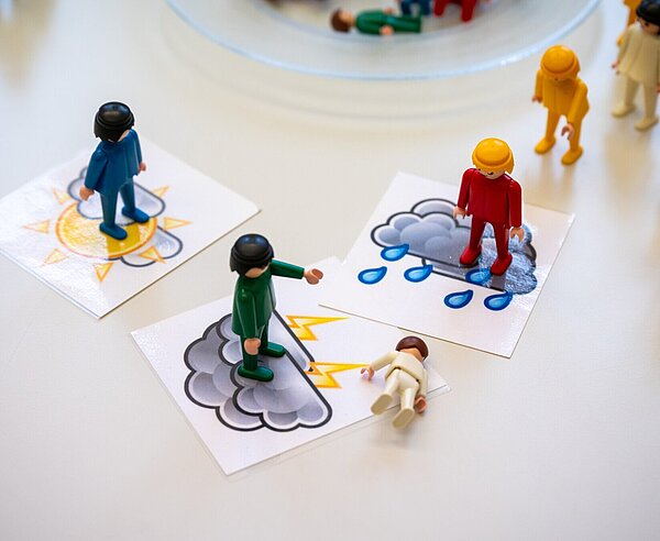 Konfliktsituation zwischen Schülern und Schülerinnen wird mit Spielfiguren am Tisch nachstellt