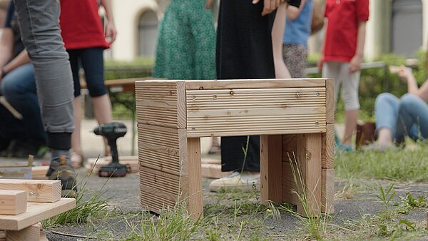 Hocker. Beine von Menschen im Hintergrund