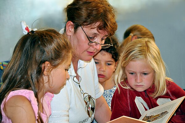 Ehrenamtliche Lesepatin liest Kindern vor.