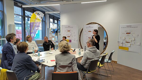 Mehrere Stakeholderinnen und Stakeholder sitzen an einem Tisch und diskutieren zu Karlsruhe 2040.