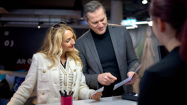 Hier ist ein Paar zu sehen, welches an der Hotelrezeption steht.