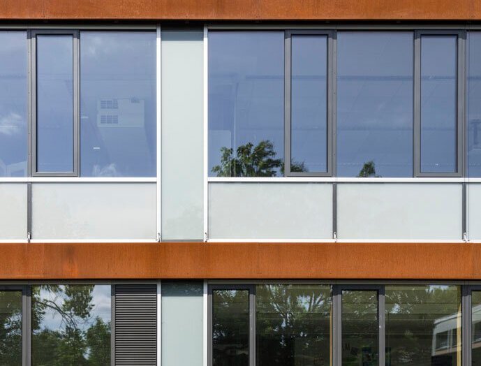 Das Bild zeigt ein Detail der Alu-Holz-Fenster mit Cortenstahl-Blenden an der Fassade.