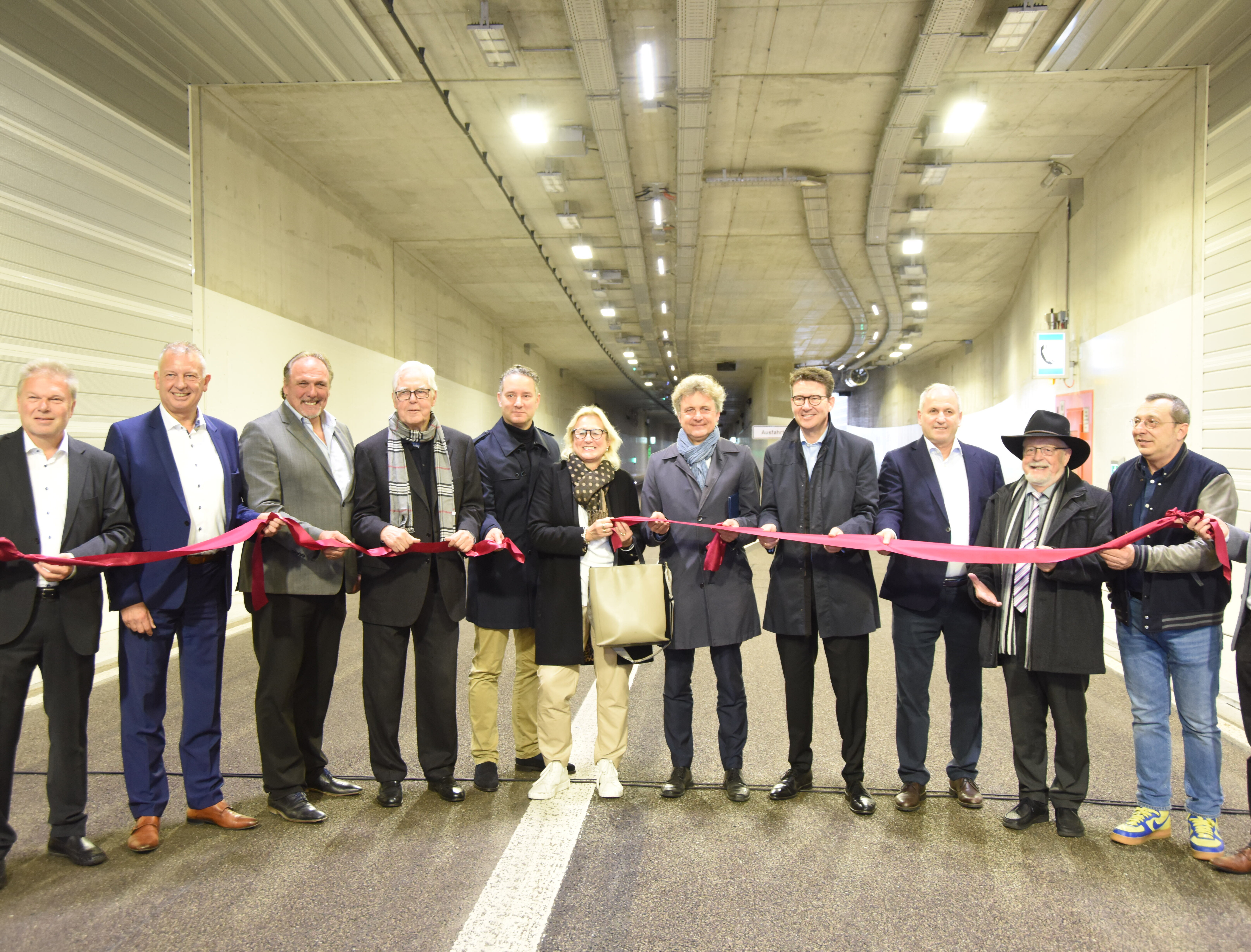 Mehrere Personen im Karoline-Luise-Tunnel halten ein rotes Band. 