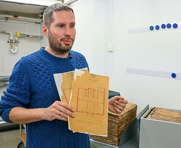 Begeistert sich für Originalquellen: Diplom-Archivar Eric Wychlacz mit restaurierten Plänen im Stadtarchiv.