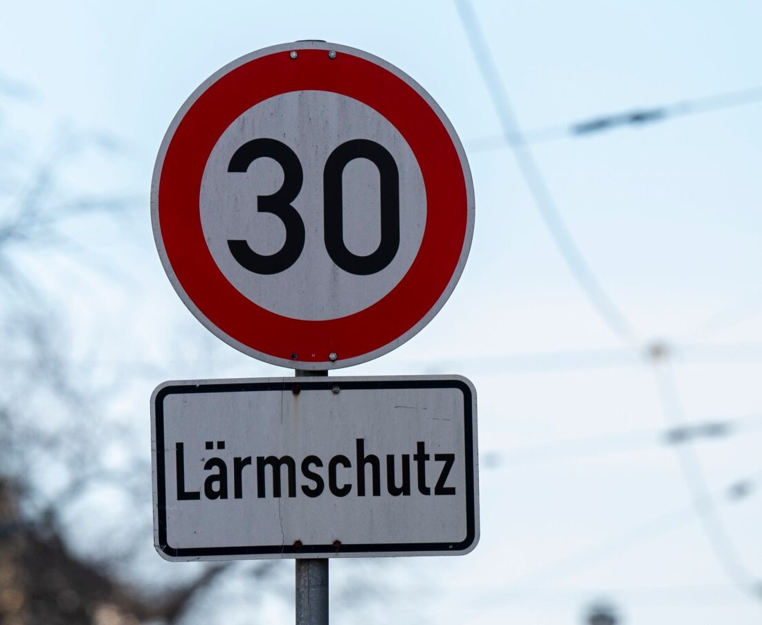 Aufnahme 30er Zone- und "Lärmschutz"-Schild vor Himmel, Bäumen und Oberleitungend der Bahn.