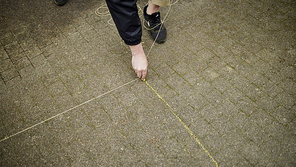 Hand mit Kreide beim vorskizzieren der Bodenbemalung auf dem Boden im Passagehof