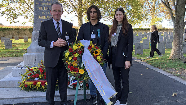 Gedenken: BM Käuflein mit den Jugendlichen Emanuel Ünal und Jessica Pieth bei der Kranzniederlegung auf dem Friedhof in Gurs.