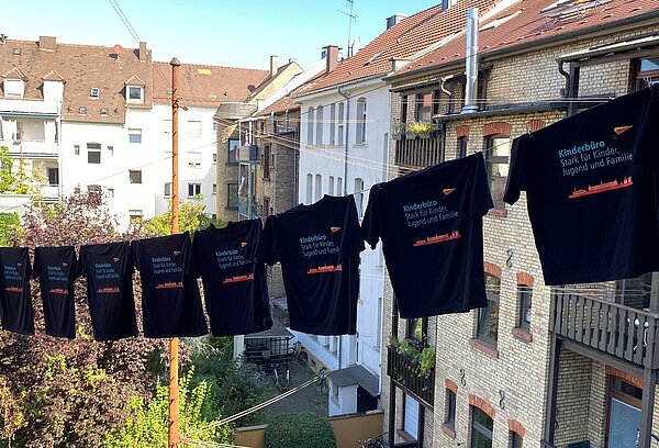 T-Shirts des Kinderbüro-Teams wehen auf auf einer Wäscheleine.