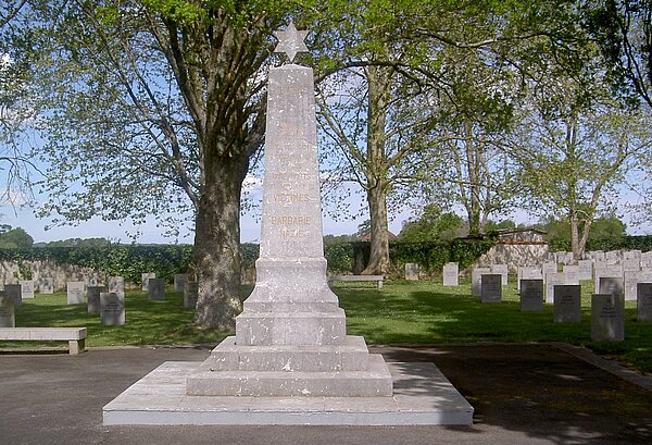 Das Bild zeigt ein weißes Denkmal mitten auf dem Friedhof