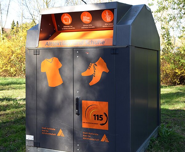 Ein Altkleider- und Schuhcontainer auf einer Wiese