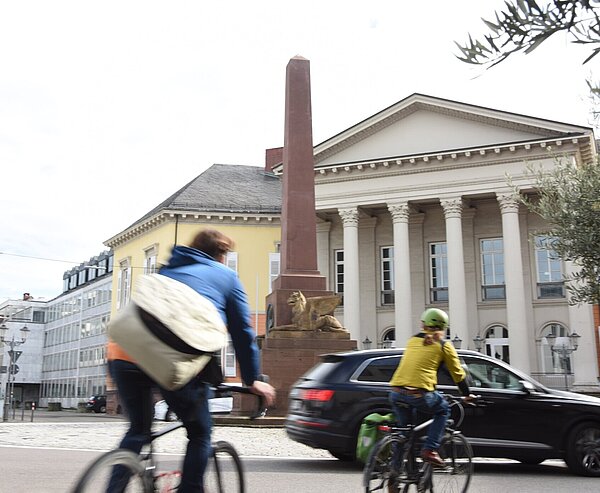 Radfahrende vor der Verfassungssäule am Rondellplatz.