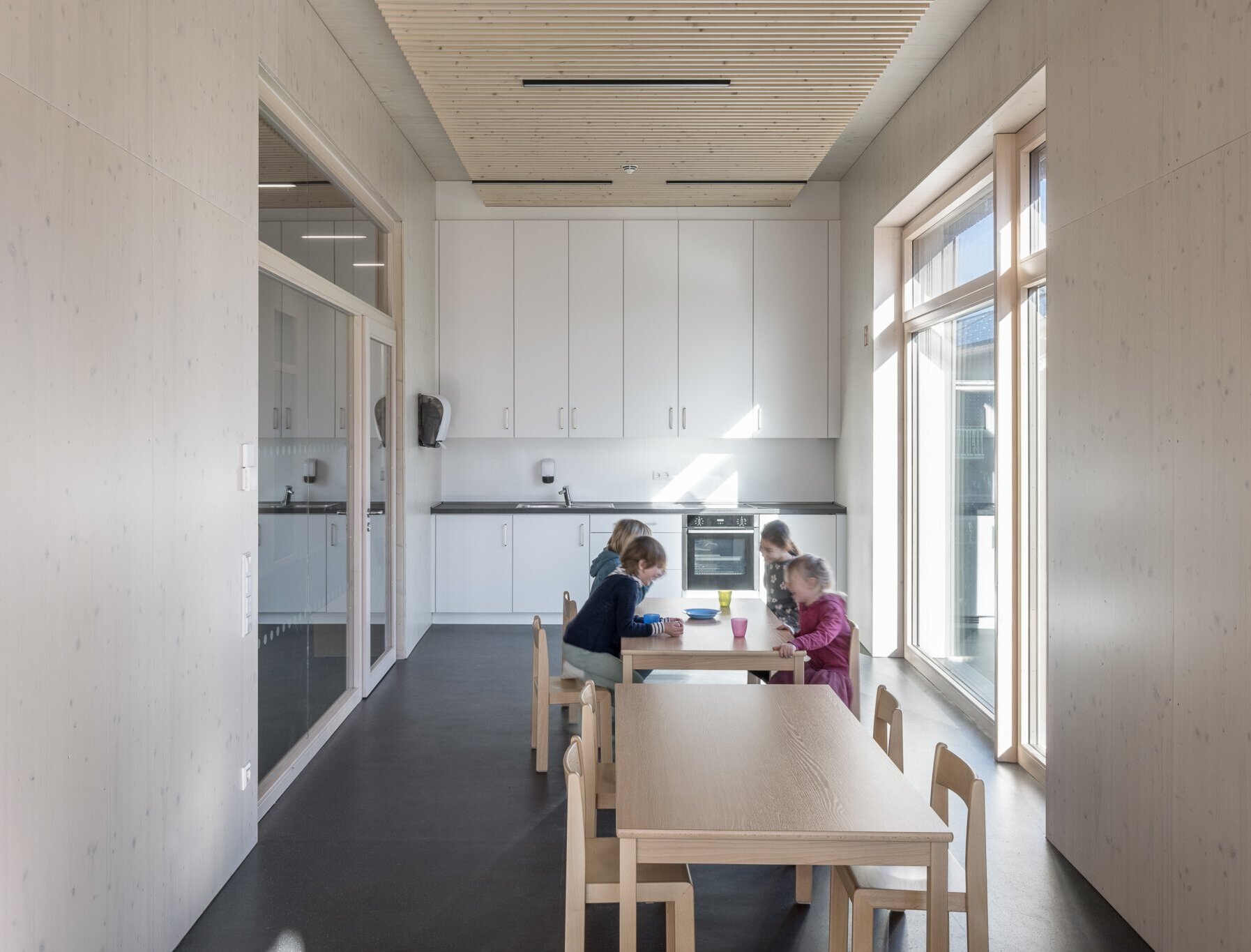 Vier Kinder sitzen in der neuen Kita-Küche an einem Tisch 