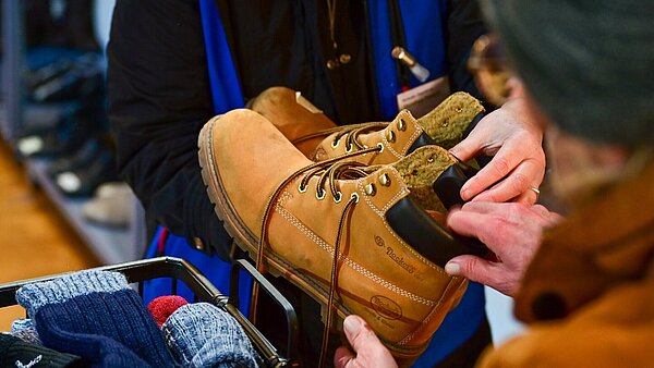 Eine Frau übergibt einem Mann ein paar Schuhe.