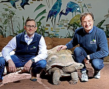 Steffen Karcher (links) und Dr. Matthias Reinschmidt im Exotenhaus bei den Riesenschildkröten: Über deren bereits vorhandenem Außengehege soll eine große Voliere gebaut werden, die dann auch von den Vögeln und Affen aus der Halle genutzt werden kann. Finanziert wird der Bau durch die Erbschaft. 