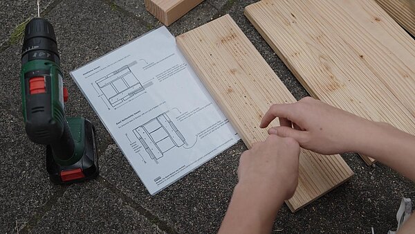 Akkuschrauber, Plan, Holz auf dem Boden, Hände