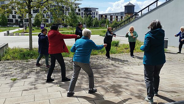 Personen stehen im City Park im Kreis und führen Koordinationsübungen durch