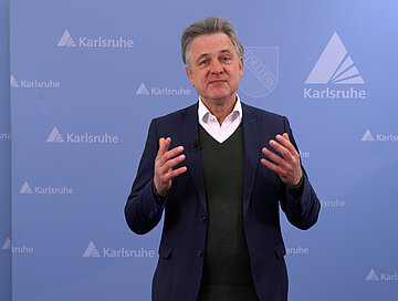 Oberbürgermeister Dr. Frank Mentrup steht vor einer blauen Wand