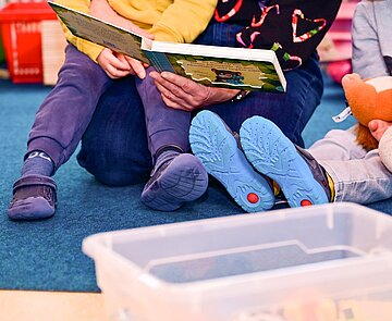 Kinder und Erzieher lesen gemeinsam ein Buch
