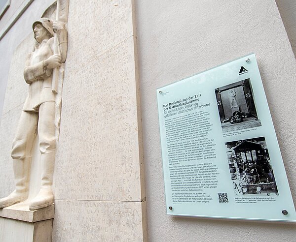 Eine Informationstafel kommentiert das Gefallenenmal im Ehrenhof des Karlsruher Rathauses.