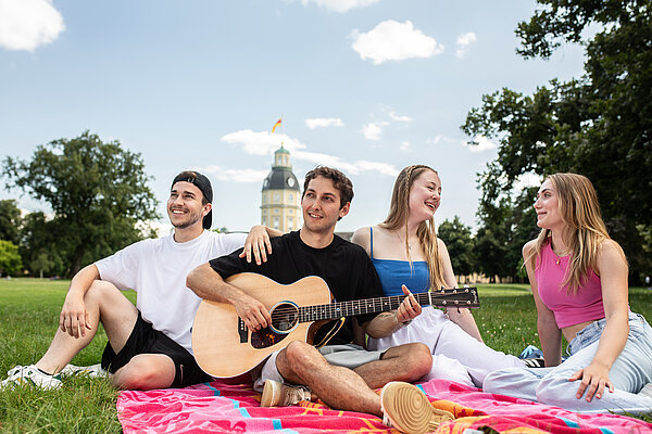 Werbefoto. Fröhliche junge Menschen auf Picknickdecke. Im Hintergrund das Karlsruher Schloss.