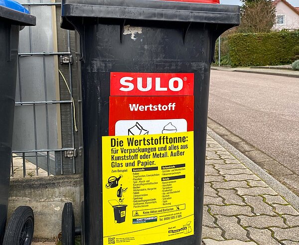 Wertstofftonne mit Gurdulic Aufkleber steht am Straßenrand
