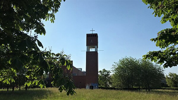 Turm mit Uhr zwischen Bäumen