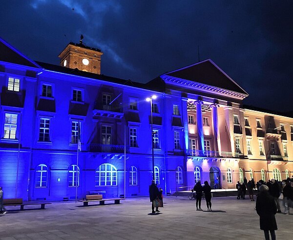 Rathaus am Marktplatz mit blau/gelber Beleuchtung am Abend.