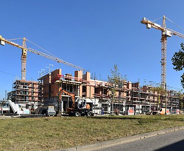 Zwei Kräne stehen an einer Hausbaustelle.