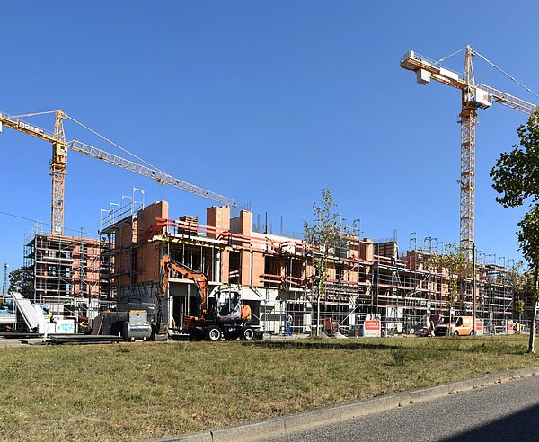 Zwei Kräne stehen an einer Hausbaustelle.