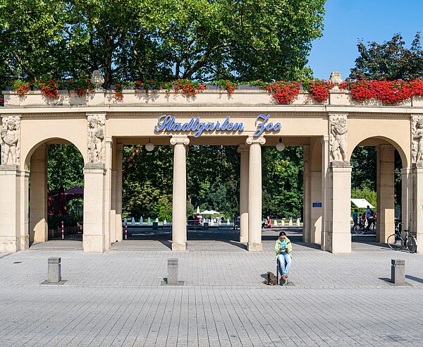 Sitzende Frau vor Eingang des Karlsruher Zoos