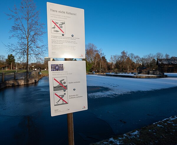 Zugefrorene Teiche in der Günther-Klotz-Anlage am Nachmittag mit Verbotsschild Tiere zu füttern , zu schwimmen und die Eisfläche zu betreten