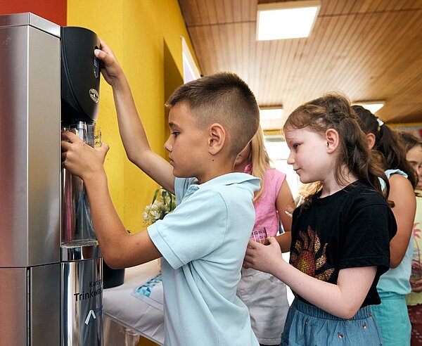 Schülerinnen und Schüler zapfen in der Südschule Neureut Wasser.