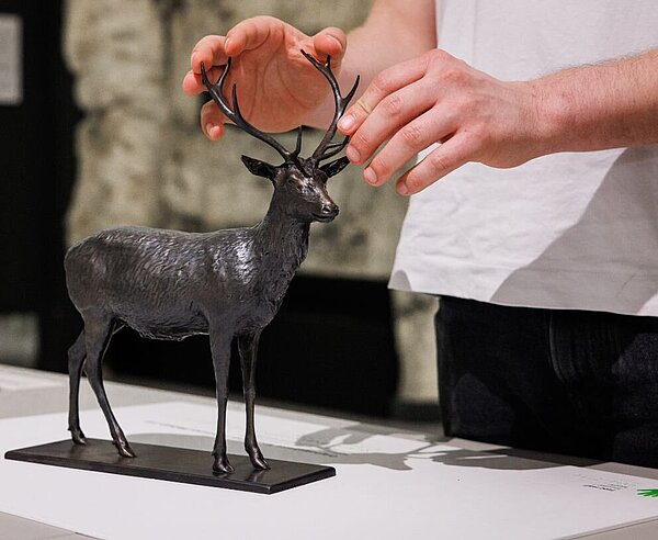 Person ertastet Figurine eine Hirsches