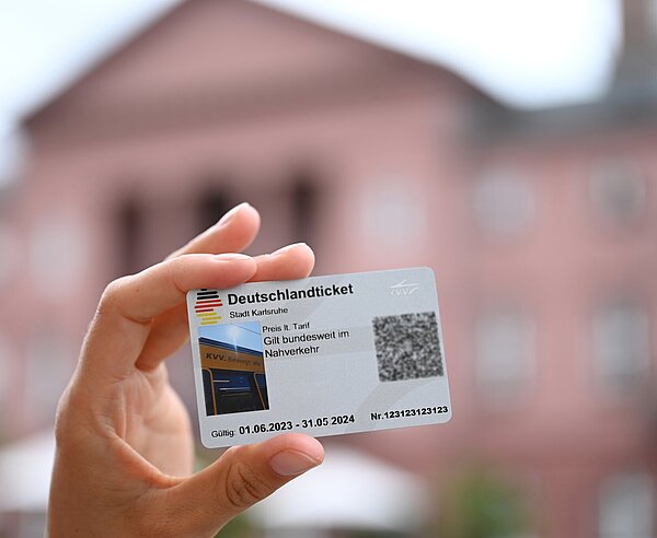 Das Deutschlandticket der KVV scharf im Vordergrund mit Rathaus unscharf im Hintergrund