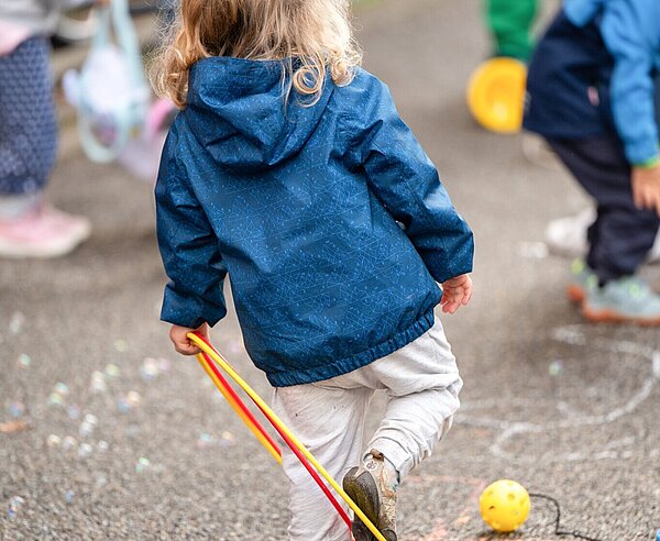 Kind spielt auf Straße mit Ring
