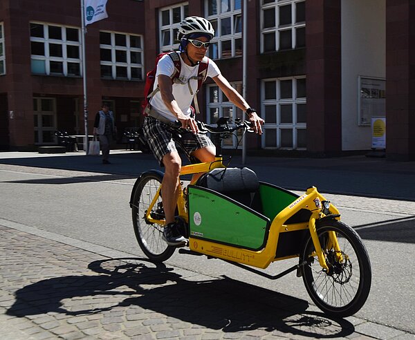 Ein Mann fährt auf einem Lastenfahrrad.