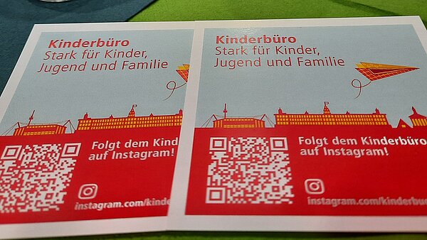 Flyer des Kinderbüros auf dem Tisch vor Tischkerzen.
