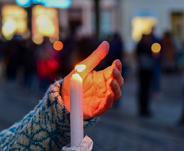 Bei der Mahnwache "Karlsruhe steht zusammen: Solidarität mit der Ukraine!" am 6. März auf dem Marktplatz wird eine brennende Kerze hochgehalten.