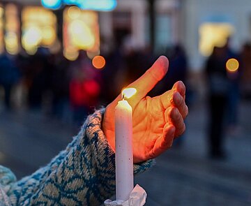 Bei der Mahnwache "Karlsruhe steht zusammen: Solidarität mit der Ukraine!" am 6. März auf dem Marktplatz wird eine brennende Kerze hochgehalten.