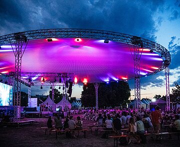 Zu sehen ist das magisch beleuchtete Dach der EFFEKTE-Bühne mitsamt Publikum bei Nacht